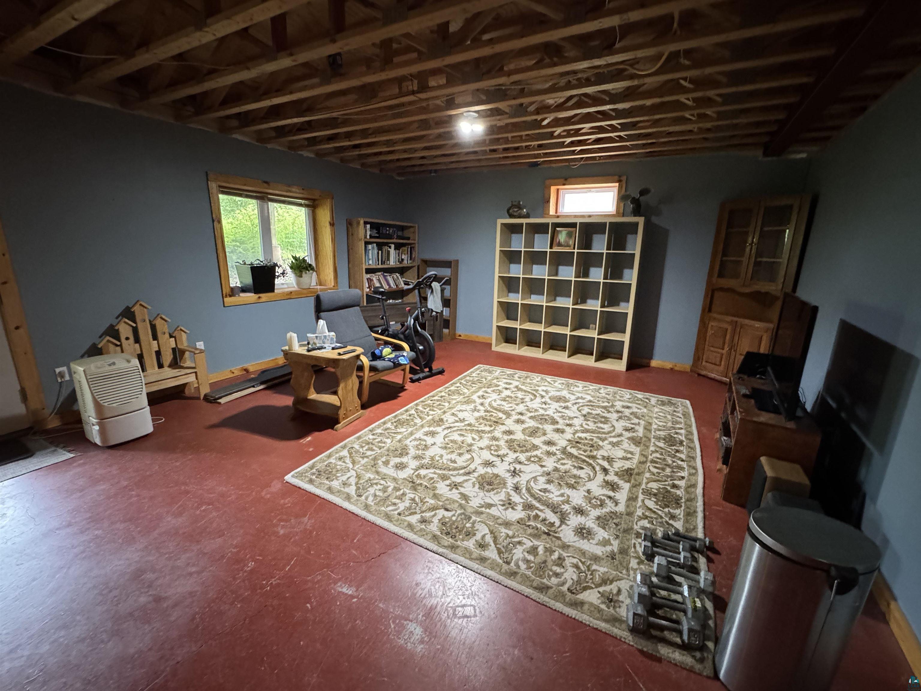 1745 Becks Road Maple, WI 54854 - Photo 29 of 46 Finished lower level space featuring exposed ceiling joists, two windows with wood trim, and painted walls