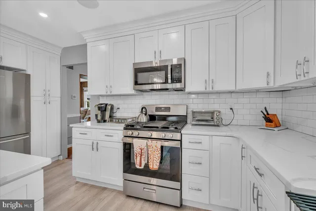 a kitchen with stainless steel appliances granite countertop grey cabinets a stove a sink and a refrigerator