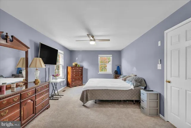 a bedroom with bed a flat tv screen and dresser