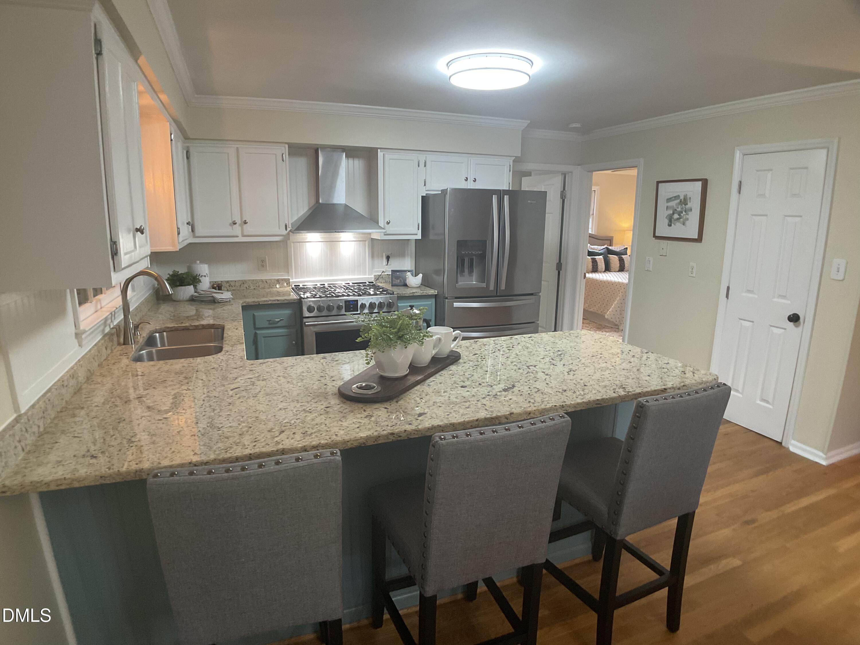 4219 Hope Valley Road Durham, NC 27707 - Photo 13 of 36 a kitchen with stainless steel appliances granite countertop a sink a stove a refrigerator with white cabinets and wooden floor