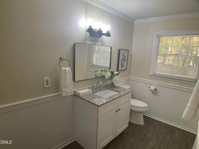 a bathroom with a granite countertop sink toilet a large mirror and a window