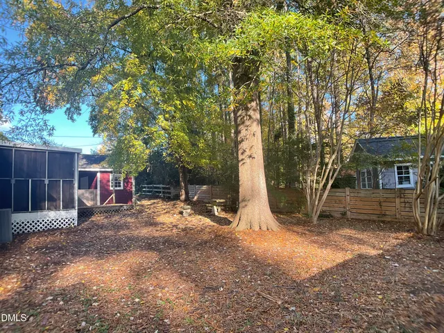 a view of a backyard with large tree and wooden fence