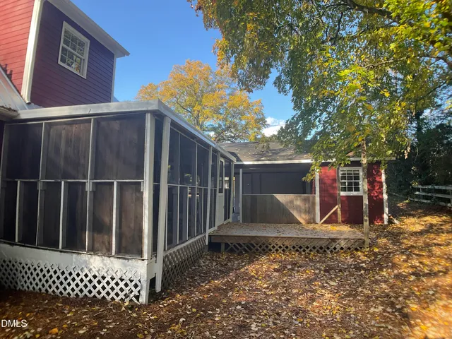 a view of a wooden house with a small yard and wooden fence