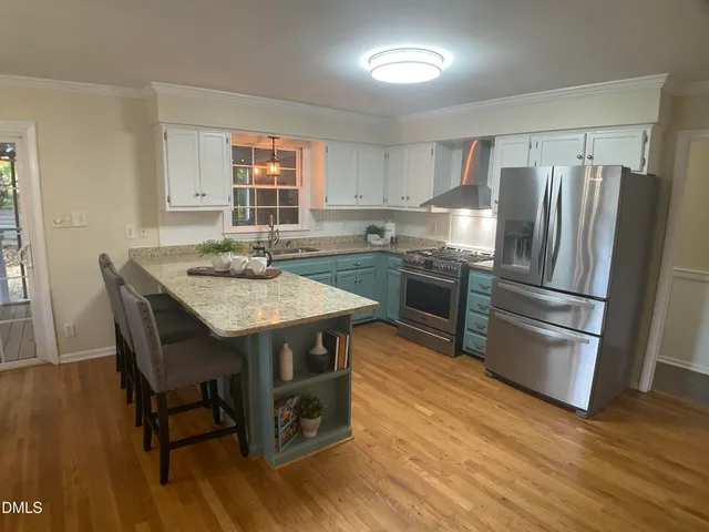 a kitchen with stainless steel appliances granite countertop a table chairs stove and refrigerator