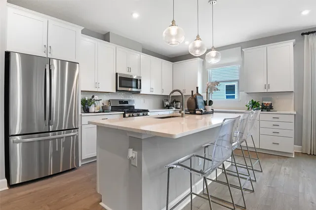 a kitchen with stainless steel appliances a refrigerator a stove a sink and white cabinets