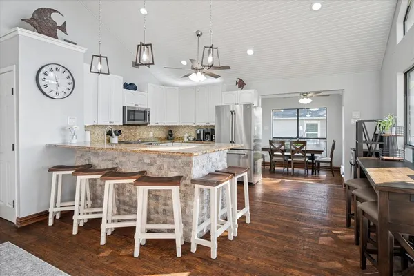 a kitchen with stainless steel appliances granite countertop a dining table chairs stove and cabinets