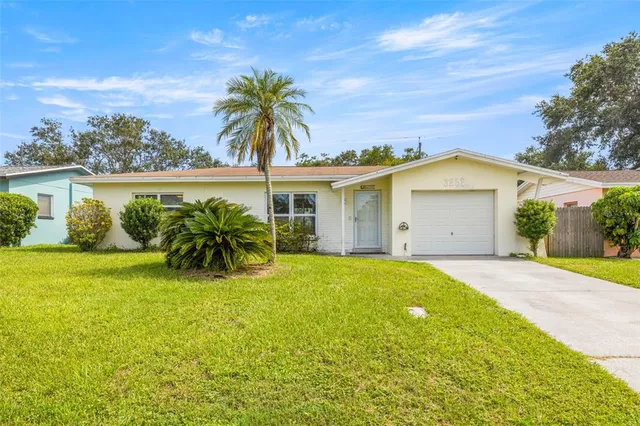 a view of a house with a yard and palm trees
