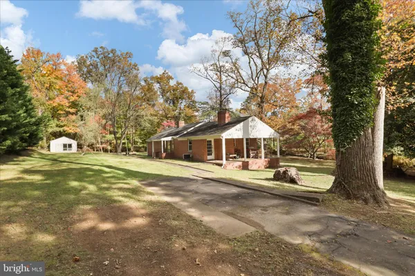 a view of a house with a yard and large trees