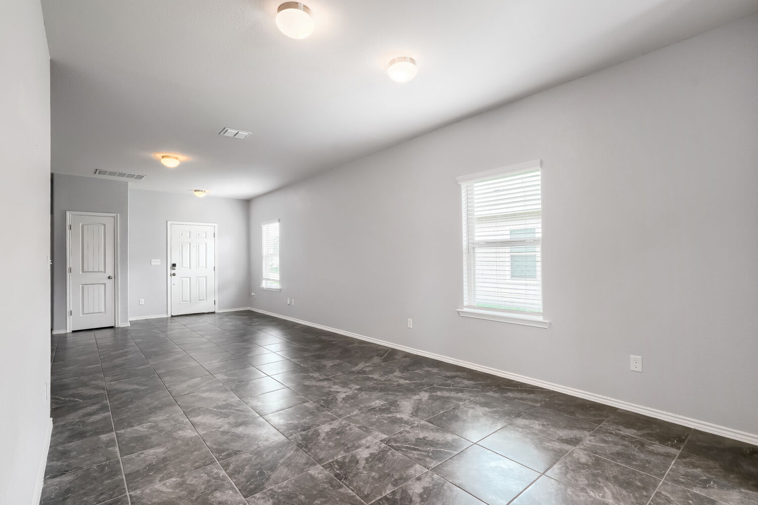 2420 Ranger Pass Seguin, TX 78155 - Photo 12 of 28 Spacious room featuring gray walls, dark large-format tile flooring, and multiple ceiling-mounted light fixtures