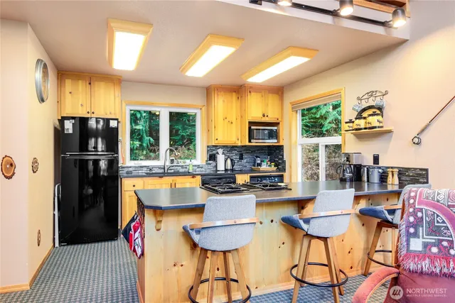 a room with stainless steel appliances granite countertop a refrigerator a stove a oven with white cabinets and wooden floor