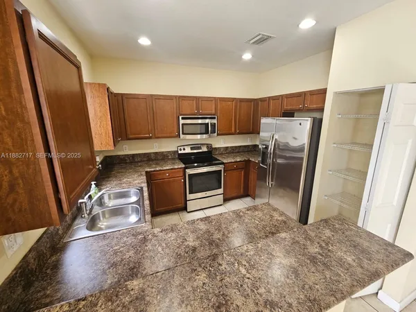 a kitchen with stainless steel appliances granite countertop a refrigerator stove and sink