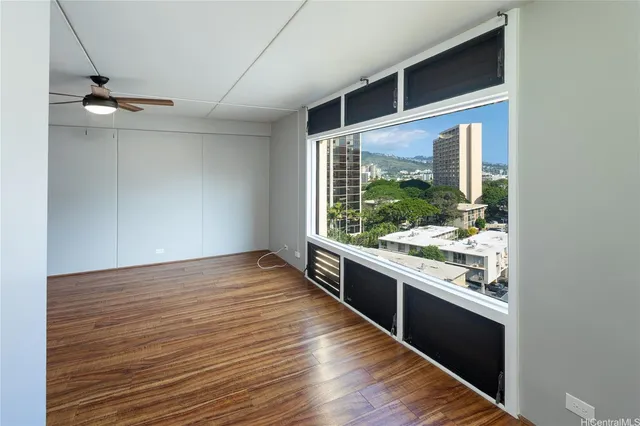 a view of an empty room with wooden floor and a window