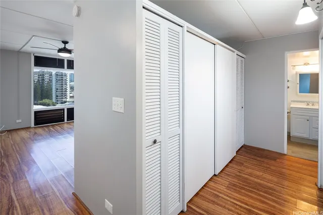 a view of a hallway with wooden floor and a bathroom