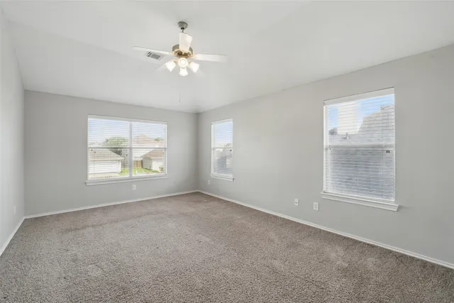an empty room with windows and chandelier fan