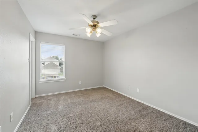 an empty room with a window and a fan