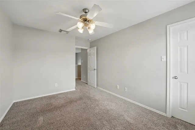 a view of an empty room with a chandelier fan