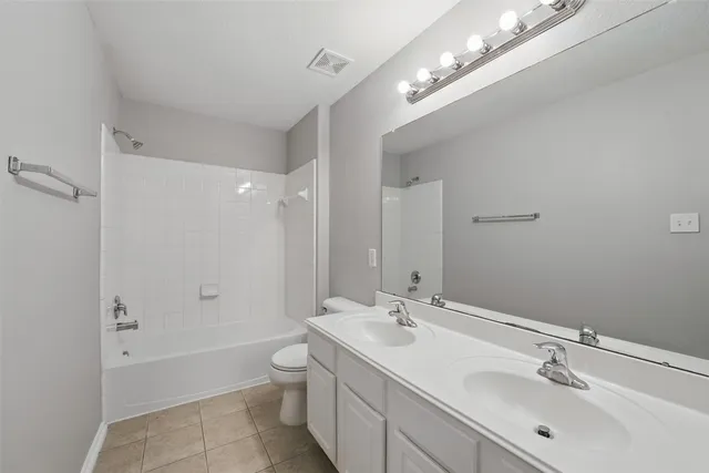 a bathroom with a double vanity sink a toilet and shower