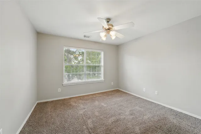 an empty room with a window and a fan