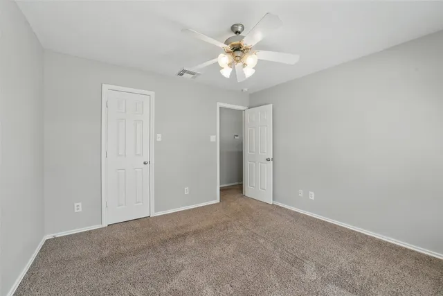 a view of an empty room with chandelier fan