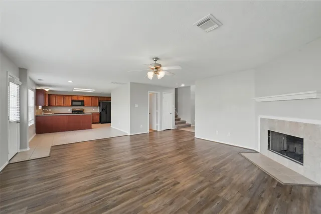an empty room with wooden floor fireplace and windows