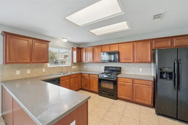 a kitchen with stainless steel appliances granite countertop a refrigerator a sink dishwasher a stove top oven and a refrigerator