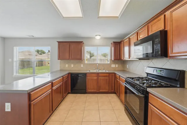 a kitchen with stainless steel appliances granite countertop a stove top oven a sink dishwasher and a microwave oven on the granite countertops