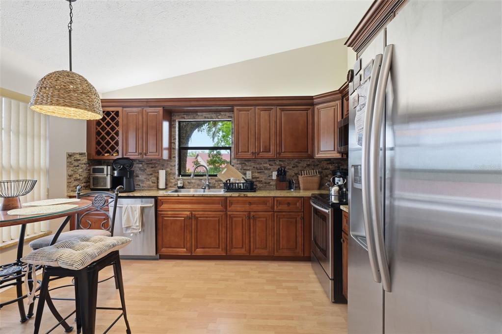 7650 Forest Trail, Unit 6 Port Richey, FL 34668 - Photo 12 of 37 a kitchen with stainless steel appliances granite countertop a refrigerator a sink dishwasher a stove and a refrigerator with wooden floor