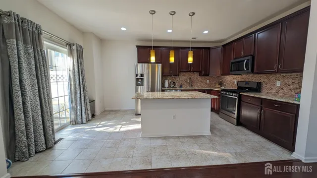 a kitchen with kitchen island granite countertop a stove top oven a sink a counter space and cabinets