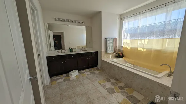 a spacious bathroom with a tub sink and mirror