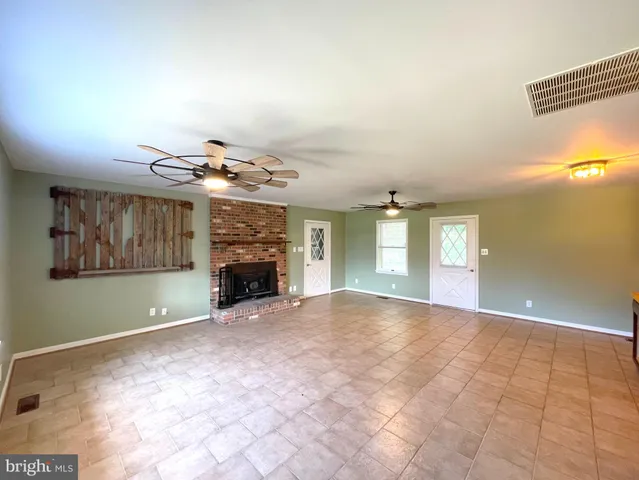 a view of an empty room with window and fireplace