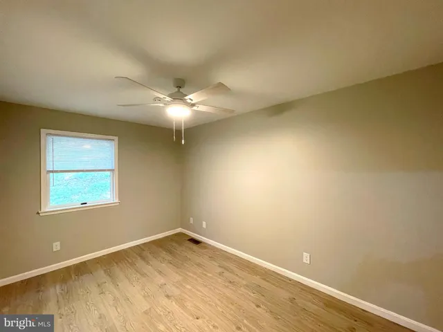 en empty room with wooden floor and fan