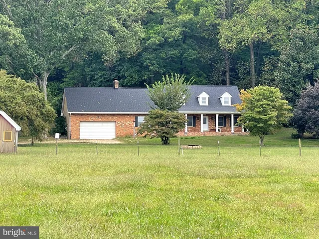 a front view of house with outdoor space and trees all around