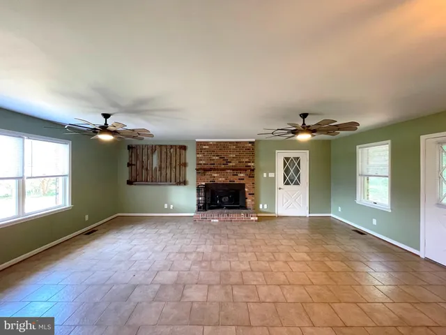 an empty room with windows and fireplace