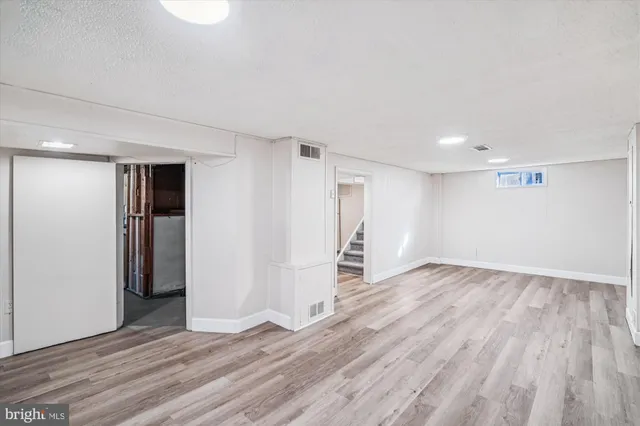 a view of an empty room with wooden floor and closet