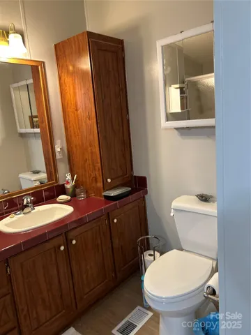 a bathroom with a toilet a sink and mirror