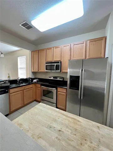 a kitchen with granite countertop a refrigerator and wooden cabinets