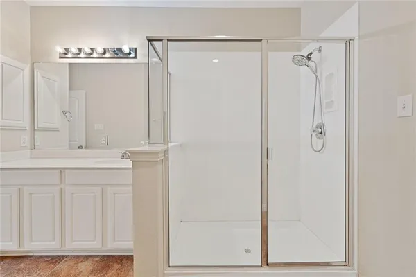 a bathroom with a shower a mirror and a glass door