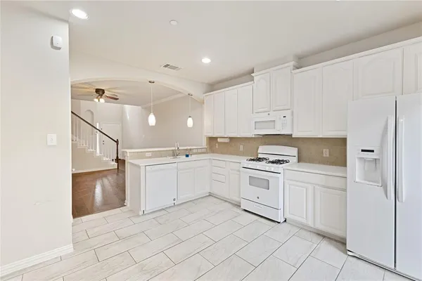 a kitchen with white cabinets and appliances