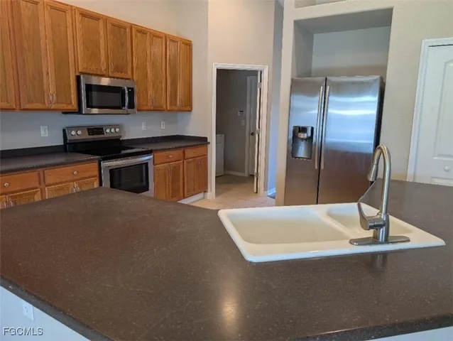 a kitchen with stainless steel appliances granite countertop a refrigerator a stove and a sink with wooden cabinets