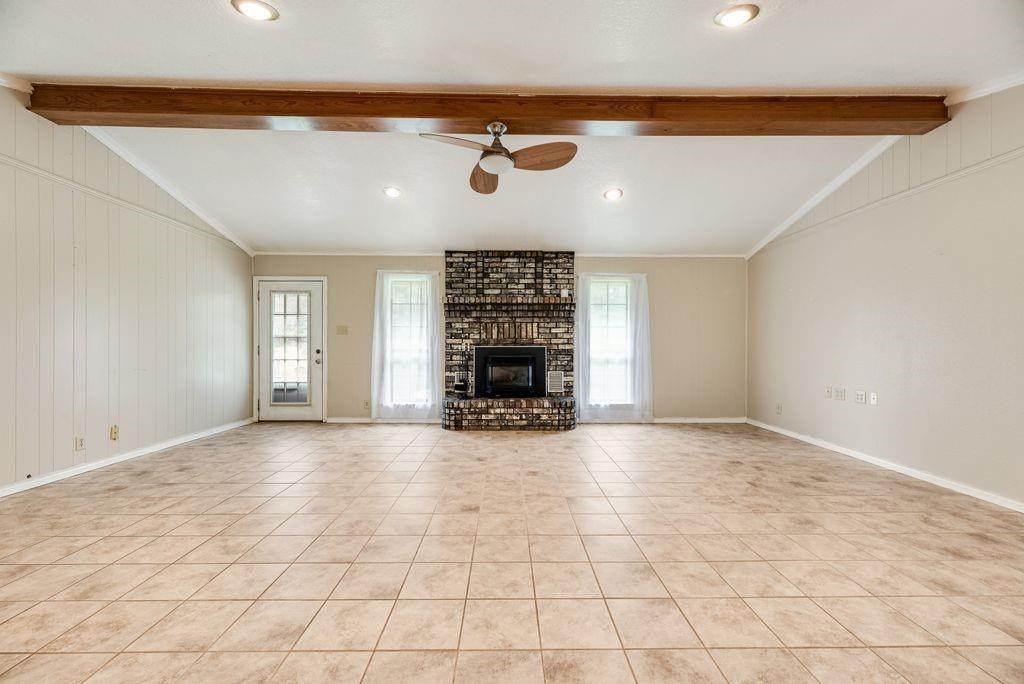 298 Butterfield Road Denison, TX 75021 - Photo 26 of 34 Spacious living area featuring neutral-toned tile flooring, a prominent brick fireplace, and dual windows