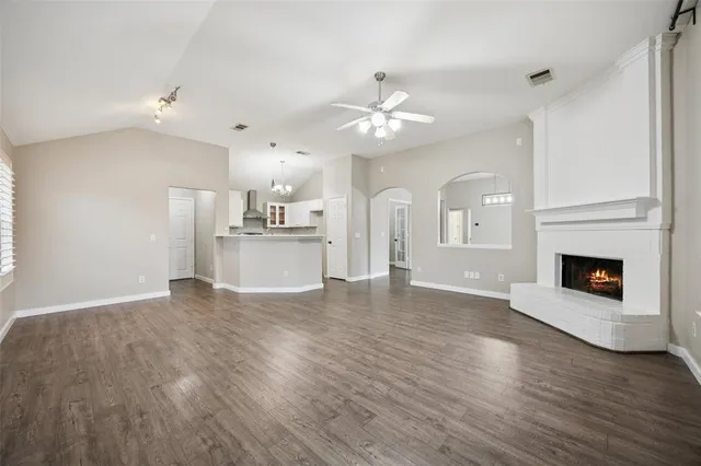 a view of a kitchen with a sink a kitchen island wooden floor and a fireplace