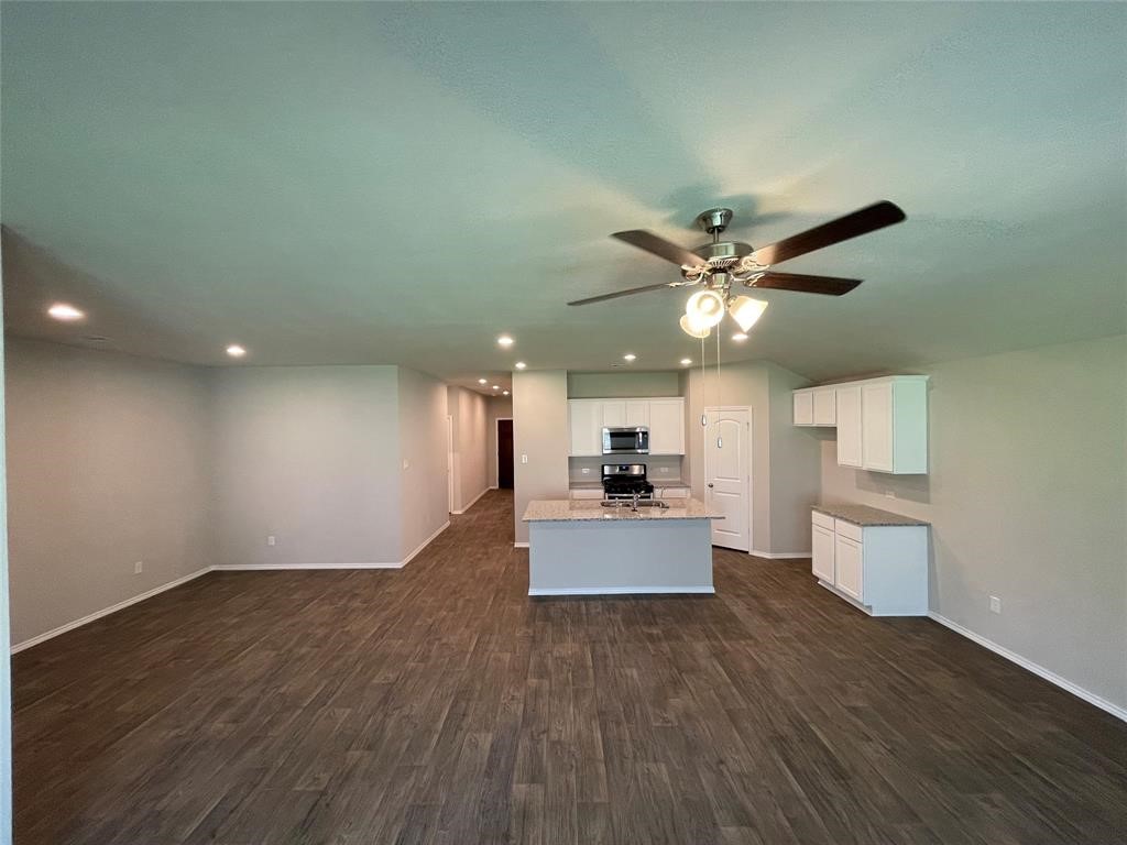 13872 Rock Island Trail Conroe, TX 77384 - Photo 2 of 32 a view of a living room a kitchen with wooden floor and a ceiling fan
