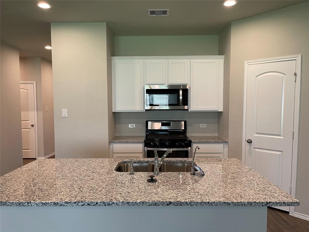 13872 Rock Island Trail Conroe, TX 77384 - Photo 3 of 32 a kitchen with granite countertop a stove a sink and a refrigerator