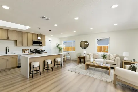 a living room with stainless steel appliances furniture and a kitchen view