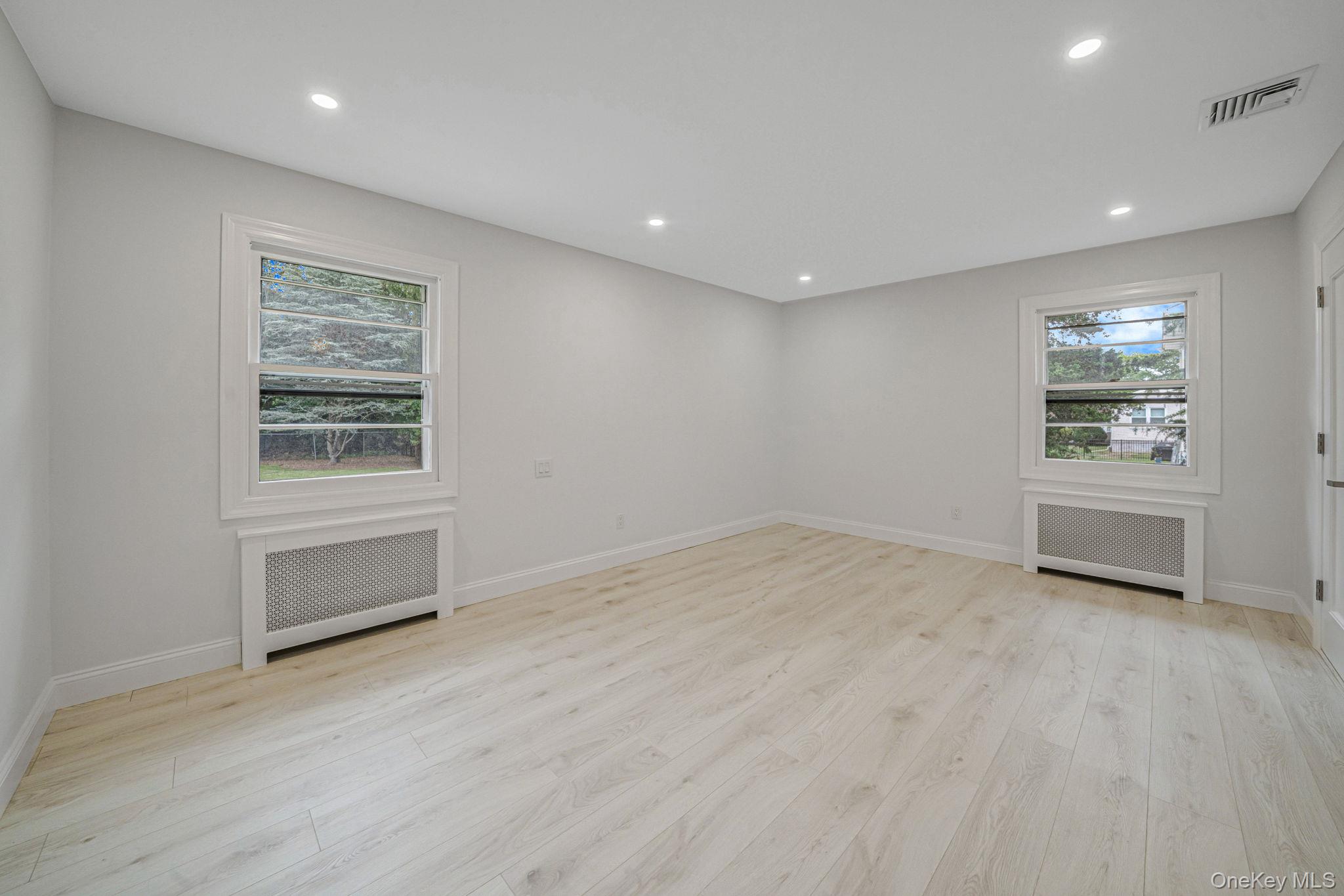 827 Aberdeen Road West Bay Shore, NY 11706 - Photo 18 of 40 Unfurnished room featuring radiator, light wood finished floors, recessed lighting, and plenty of natural light