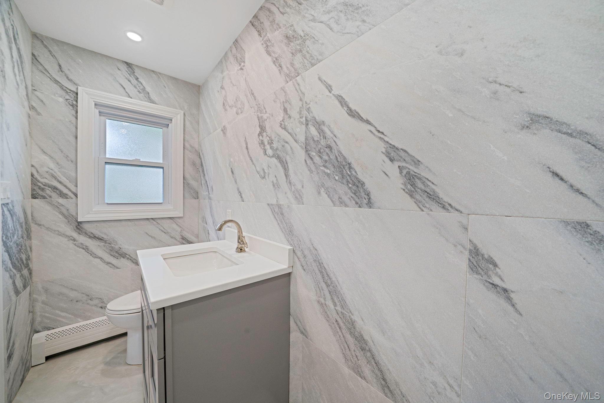 827 Aberdeen Road West Bay Shore, NY 11706 - Photo 20 of 40 Bathroom featuring tile walls, vanity, stone wall, a baseboard heating unit, and recessed lighting