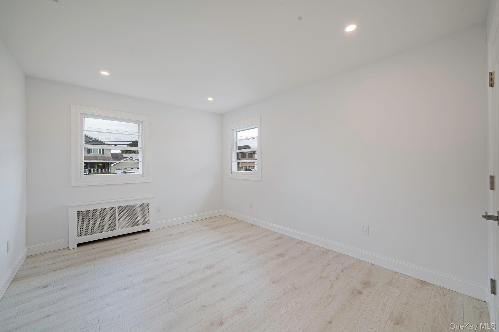 827 Aberdeen Road West Bay Shore, NY 11706 - Photo 27 of 40 Unfurnished room featuring radiator heating unit, recessed lighting, and light wood-style flooring