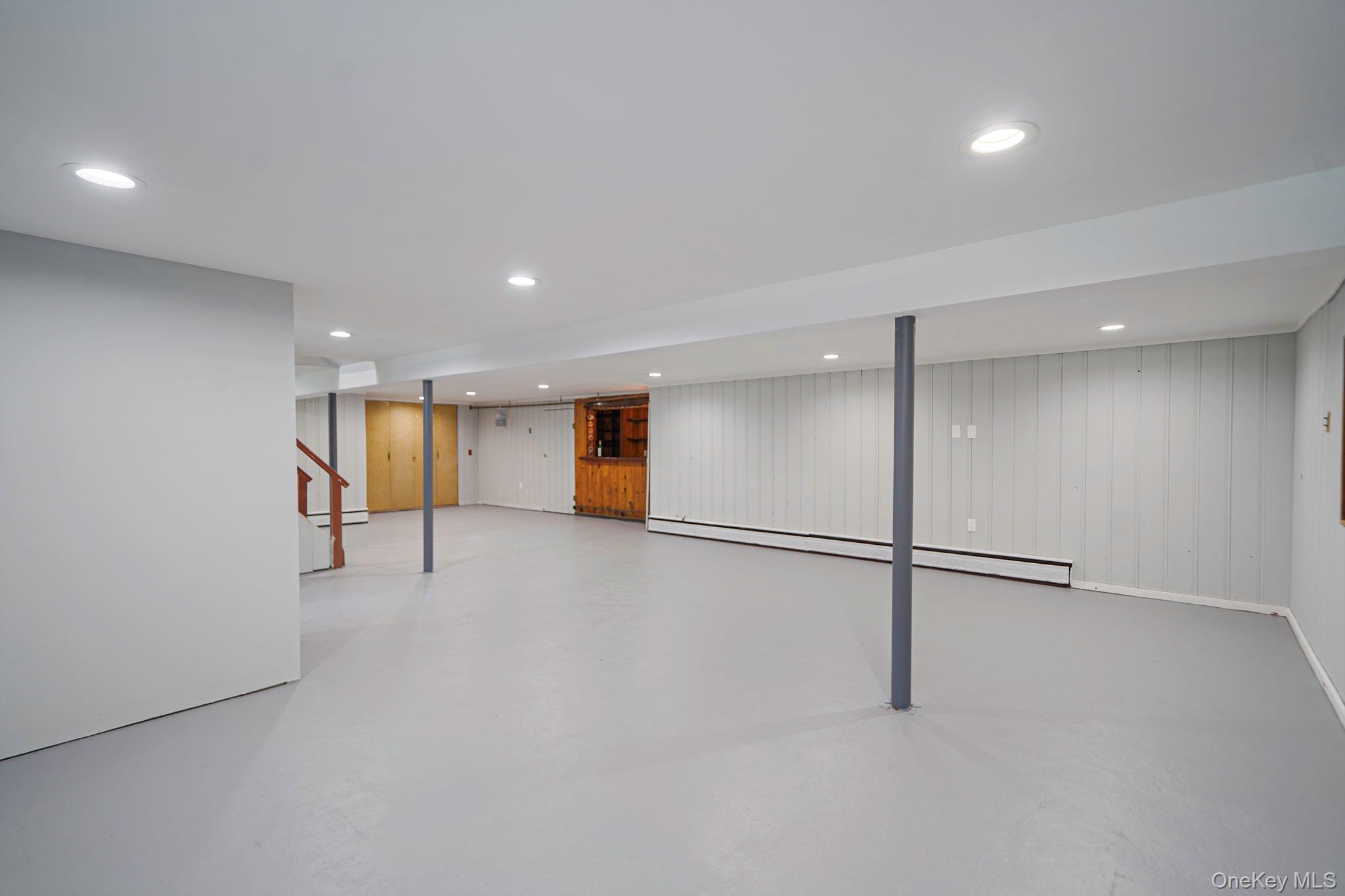 827 Aberdeen Road West Bay Shore, NY 11706 - Photo 31 of 40 Finished below grade area with stairs, a baseboard radiator, recessed lighting, and wood walls