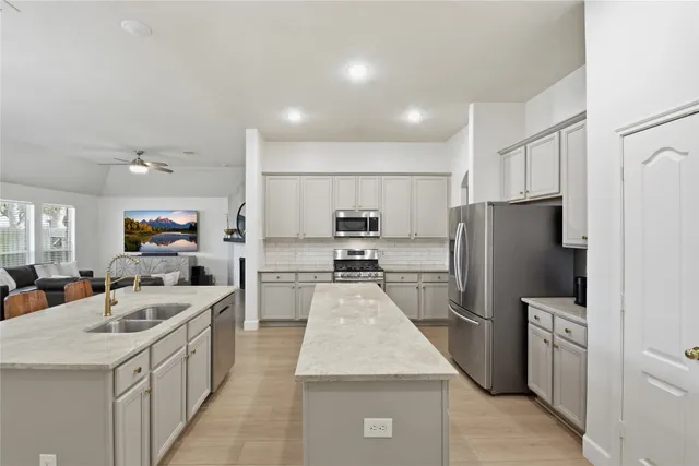 a large kitchen with stainless steel appliances kitchen island a stove a refrigerator a oven and a sink with large countertops