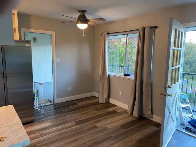 a view of a room with wooden floor and a ceiling fan